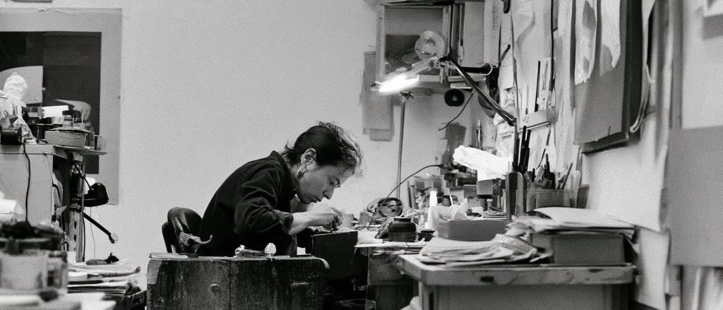 Un artiste concentré travaille sur un projet créatif dans son atelier, entouré de matériaux divers et d'outils, sous une lumière douce